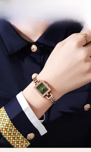 Detailed shot of emerald green square quartz watch with rose gold mesh band and diamonds