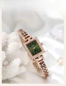 Detailed close-up of a rectangular rose gold watch with a green dial on silk background