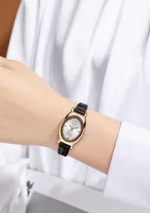 Close-up of elegant oval rose gold quartz watch with black leather strap on a female wrist
