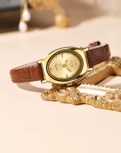 Macro detail of tonneau shaped gold watch case and textured brown leather strap