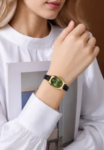 Elegant gold oval quartz watch with vintage green dial on a model's wrist with magazine