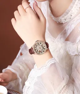 Detail of rose gold skeleton watch with rhinestone bezel and brown leather strap