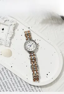 Détail d'une montre élégante avec chiffres romains et bracelet en acier argent et or rose