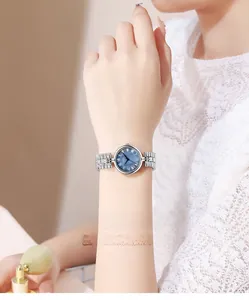 Close-up of a vintage silver watch with blue sunray dial and Roman numerals on a wrist