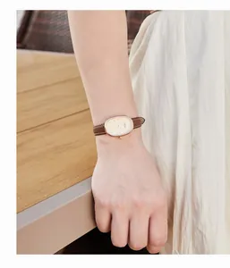 Nahaufnahme der ovalen Damenuhr in Roségold mit braunem Lederarmband am Handgelenk