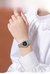 Detail of steel strap watch with black dial and Roman numerals on woman wrist