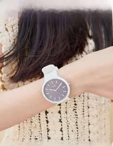 Close-up of a minimalist quartz watch with white silicone strap and grey dial on wrist
