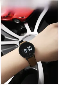 Close-up of digital sports watch with LED display and brown strap against a car backdrop