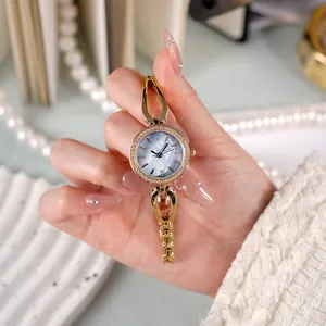 Montre bracelet de luxe dorée pour femme avec cadran nacre bleue et lunette cristal