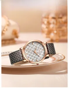 Detail of rose gold quartz watch with monogram leather strap on white ceramic plate