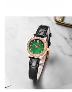 Close-up of green dial watch with crystal bezel on white marble background