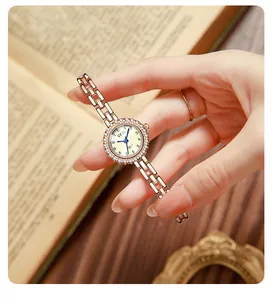 Detail of GEDI rose gold watch with crystal bezel and link strap on a book background