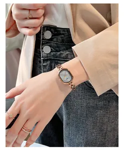 Detail of rose gold oval watch with dark grey sunray dial and elegant metal chain strap
