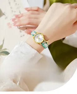 Detail of GEDI watch featuring golden fishtail pendant and teal floral strap on wrist