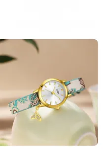 Detail of GEDI quartz watch with floral fabric strap and a gold whale tail charm