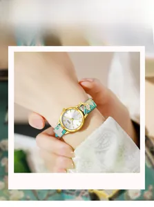 Close-up of gold quartz watch with embroidered cyan strap and sparkling fishtail pendant