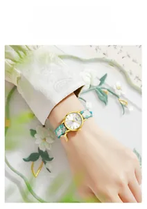 Detail of GEDI quartz watch with floral strap and gold fish tail charm on wrist