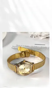 Close-up of gold oval sunray dial with date window and steel mesh band quartz watch