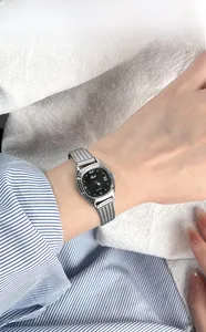 Elegant silver rectangular quartz watch with black dial on a woman's wrist with fabric