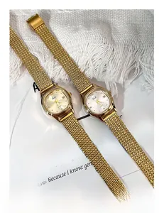 Detail view of gold mesh strap watches with champagne and white rectangular dials