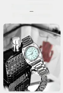 Detail of square Gedi quartz watch with light green dial resting on a perfume bottle