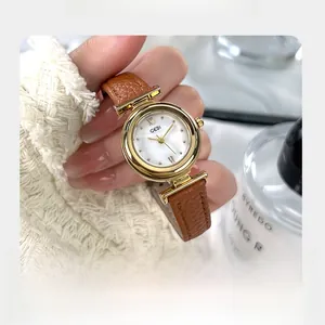 Close-up of elegant gold watch with mother of pearl dial and brown leather strap