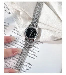 Macro shot of silver mesh strap quartz watch with black dial and crystal markers