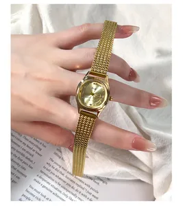 Elegant gold mesh strap watch for women shown on a model against a soft fabric background