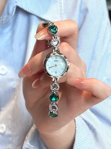 Detail of GEDI bracelet watch featuring heart-shaped emerald green crystals and diamonds