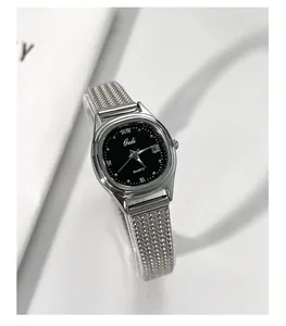 Detail shot of a silver mesh strap women's watch with a black dial and date window