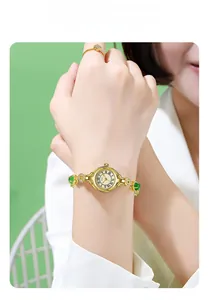 Detail of Gedi gold watch with green stones and roman numerals on model wrist