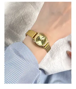 Close-up of golden vintage quartz watch with mesh strap and date window on female wrist