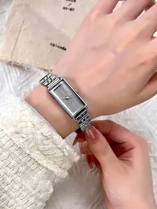 Close-up of a silver rectangular vintage steel watch on a female wrist with white knit sleeve