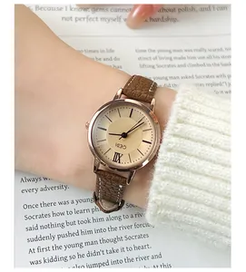 Close-up of GEDI vintage quartz watch with rose gold case and brown leather strap on book