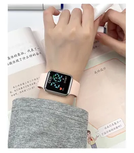 Detail shot of a pink silicone sports watch with a digital display over an open book