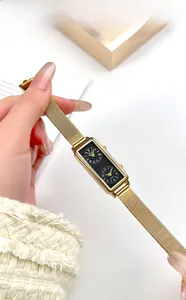 Close-up of golden rectangular dual-dial watch with stainless steel mesh strap on hand