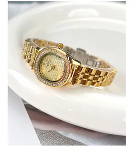 Vue détaillée d'une montre à quartz dorée avec lunette en diamant sur plat blanc