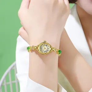 Elegant gold vintage women's watch with green stone inlays and Roman numeral dial