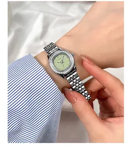 Gros plan d'une montre de luxe pour femme en acier avec lunette diamantée et cadran vert