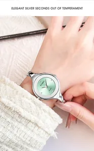 Close-up of minimalist silver quartz bangle watch with elegant mint green dial on wrist