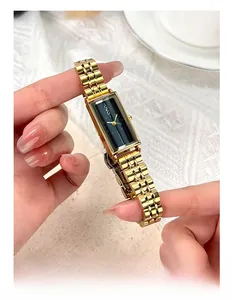 Macro shot of rectangular black dial and gold stainless steel link strap on a watch