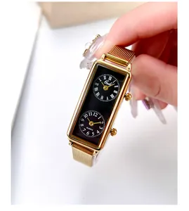 Close-up of gold rectangular watch with dual black dials and Milanese mesh band