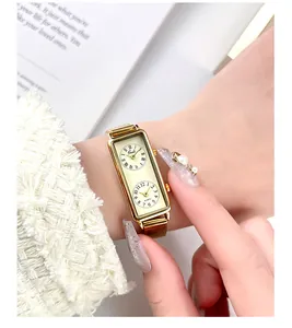 Close-up of elegant gold rectangular dual-dial quartz watch on woman's wrist
