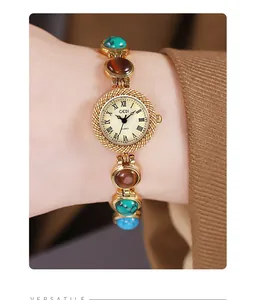 Détail d'une montre à quartz vintage dorée avec pierres colorées sur bracelet élégant