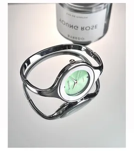 Detail view of a silver bangle watch featuring a mint green dial and white ceramic bezel
