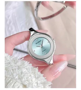 Detail of silver bangle watch with light blue dial and rhinestone markers on wrist