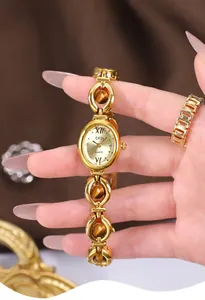 Close-up of golden bracelet watch featuring tiger eye stones and oval emerald-style dial