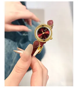 Gros plan sur l'élégante montre GEDI avec cadran rouge soleil et bracelet en cuir au poignet