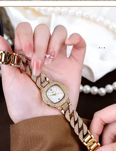 Close-up of golden quartz watch with luxury rhinestones on dial and metal bracelet