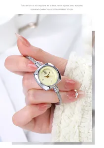 Wrist detail of a silver square watch with steel cable strap on a female wrist